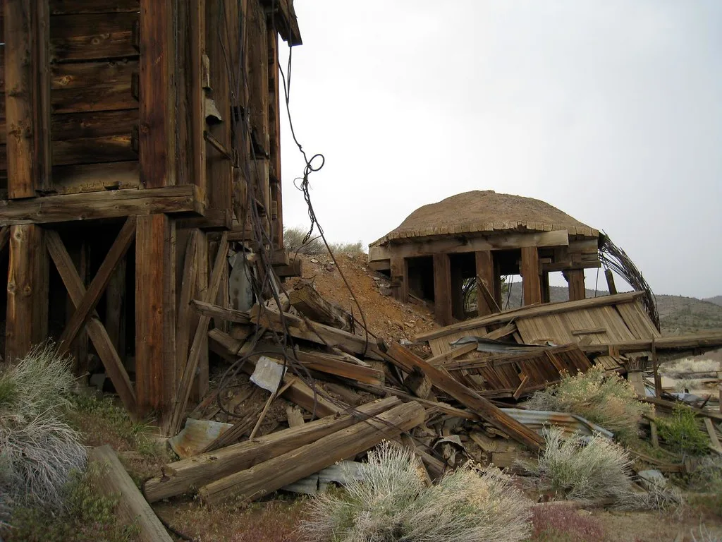 Collapsed wooden structures and hanging cables on dry ground.