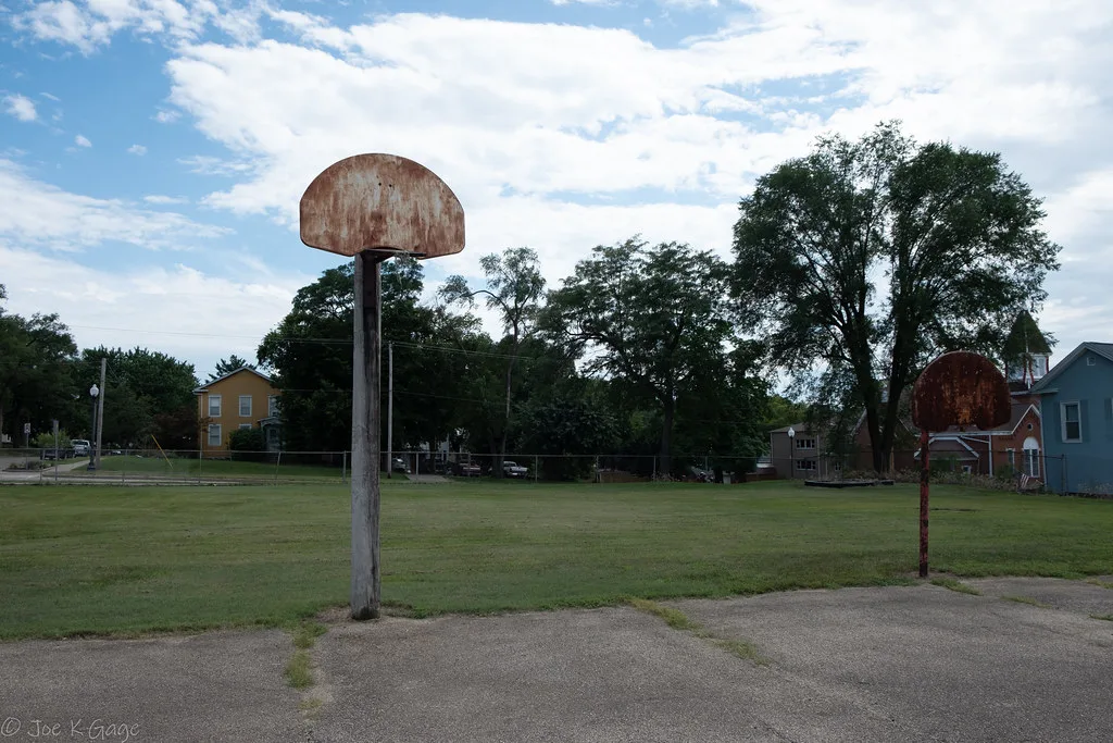 Old basketball court with rusty backboards and missing hoops.