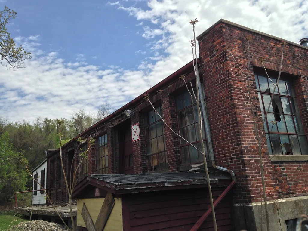Old brick building with broken industrial windows and a deteriorated canopy.