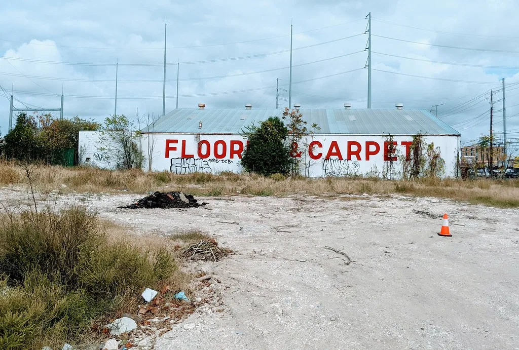 Old warehouse with a flooring sign, graffiti and vegetation.