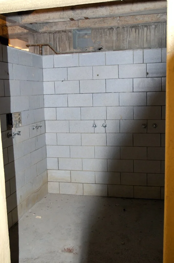 Old tiled communal showers with missing fittings.