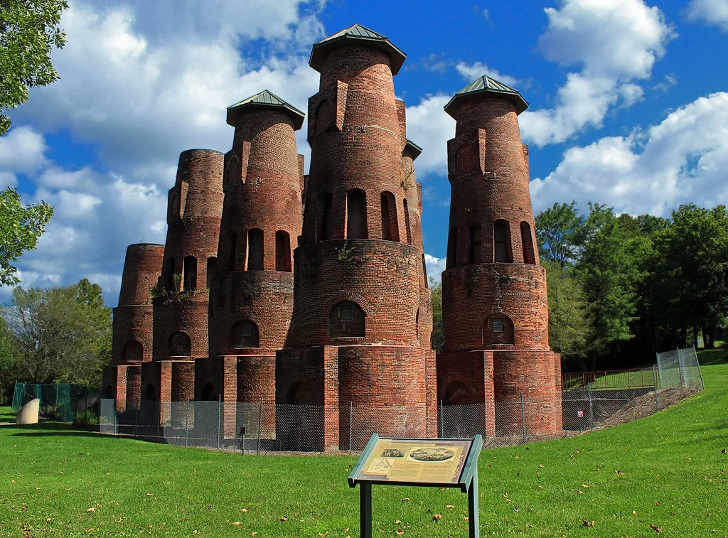 Red brick industrial towers behind a fence.