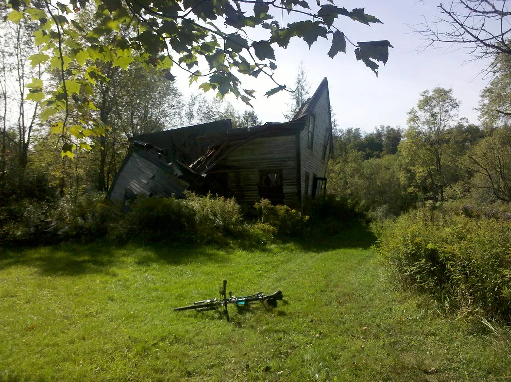 Abandoned wooden house with a collapsed roof and wall.