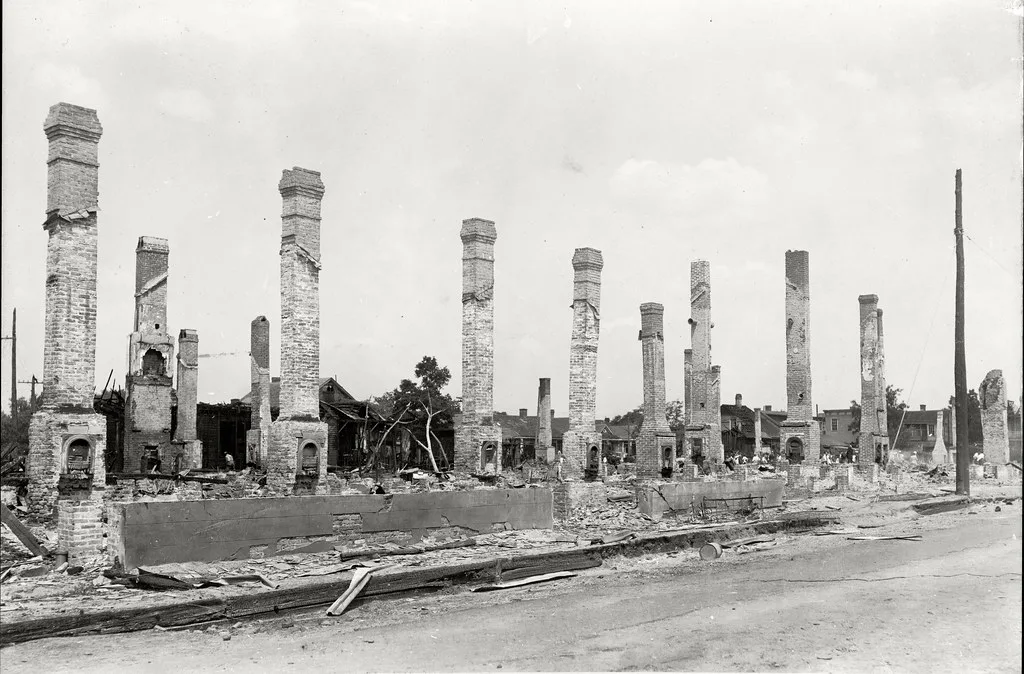 Photographie ancienne en noir et blanc de rangées de cheminées de briques parmi des fondations et débris de bâtiments détruits.