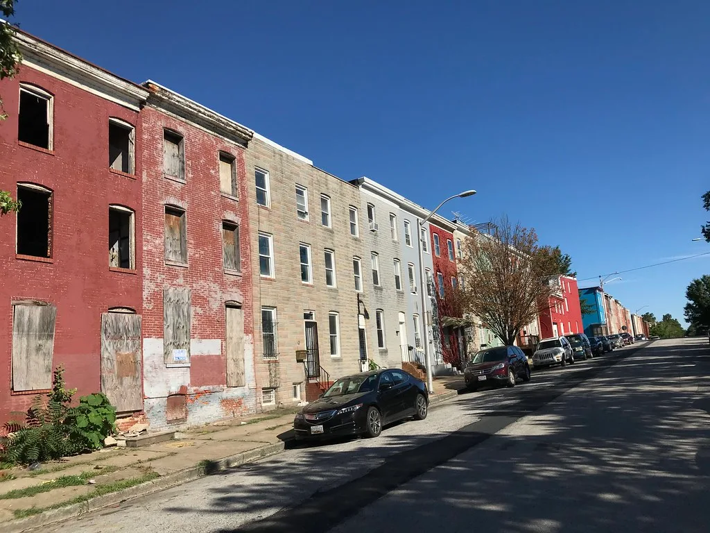 Façades de maisons de brique rouges avec ouvertures béantes et portes barricadées dans une rue.