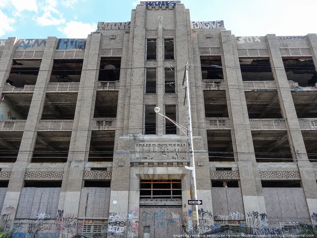 Industrial facade with large empty openings and graffiti-covered walls.