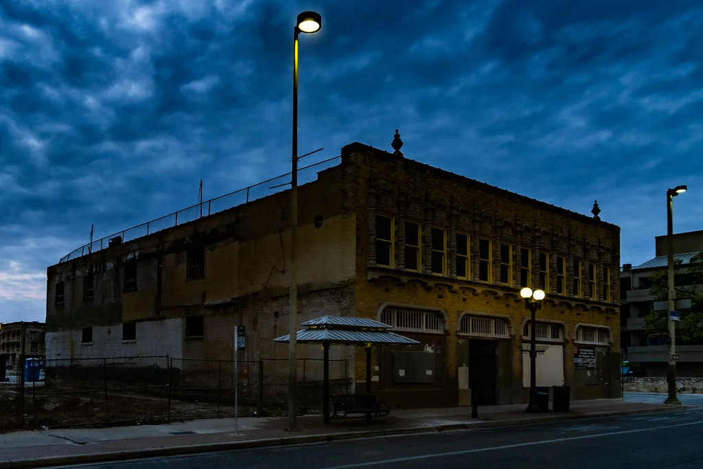 Ancien immeuble aux accès condamnés au crépuscule près d’un abri de transport.