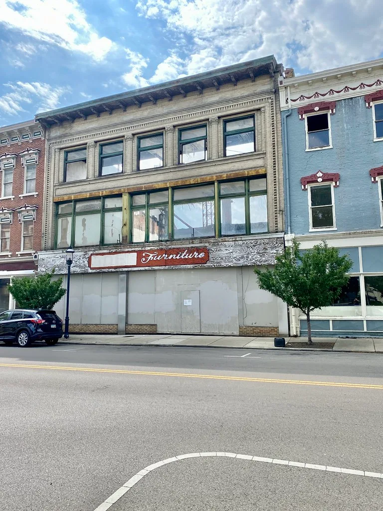 Ancien magasin aux accès condamnés sous une enseigne de meubles.