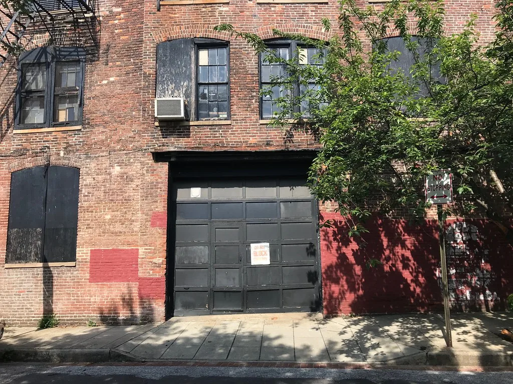 Porte de garage sombre dans la façade en brique d'un bâtiment industriel de Baltimore.