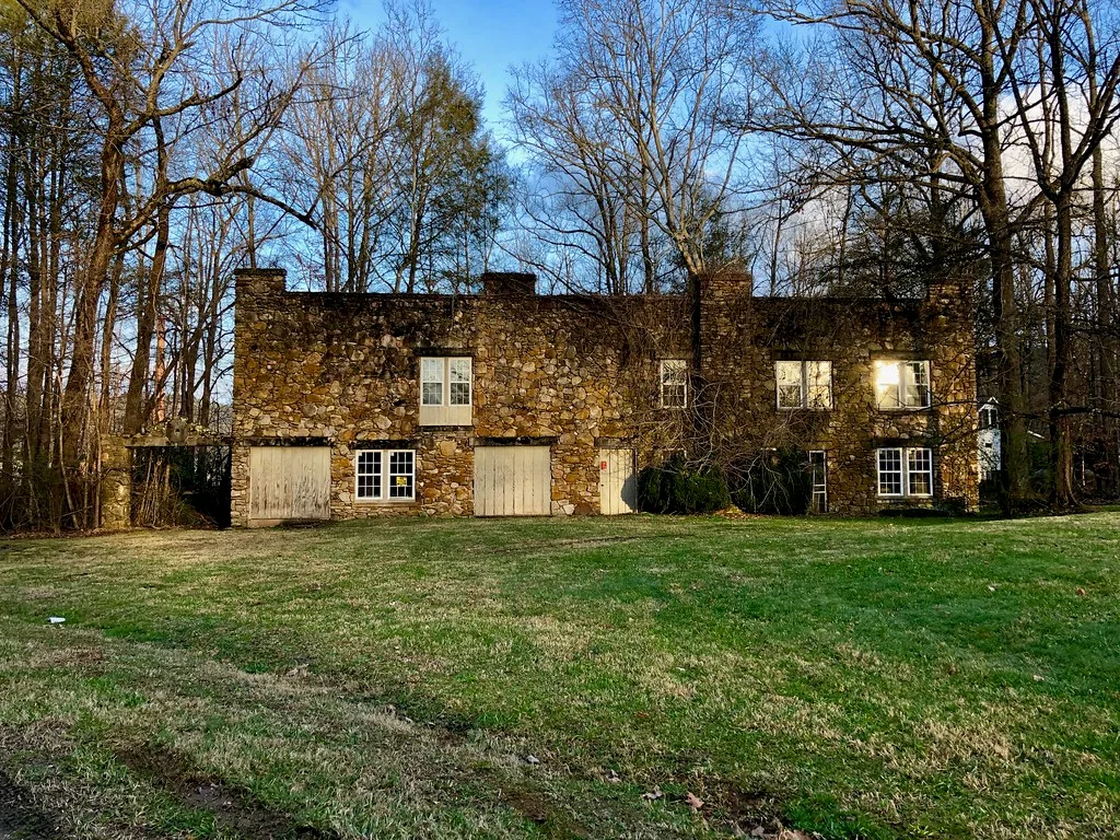 Bâtiment en pierre à deux niveaux sur Neil Hay Road, entouré d'arbres.