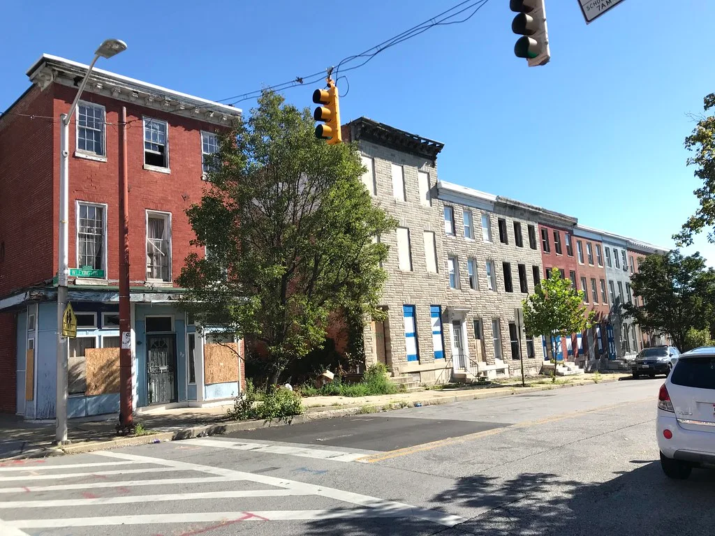 Row of urban buildings with empty or boarded windows.