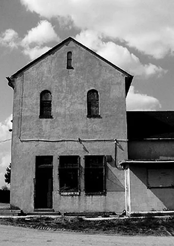 Ancien bâtiment à pignon aux ouvertures vides, en noir et blanc.