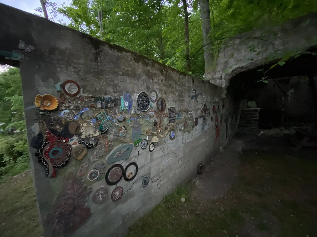 Ruined wall decorated with mosaics among trees.