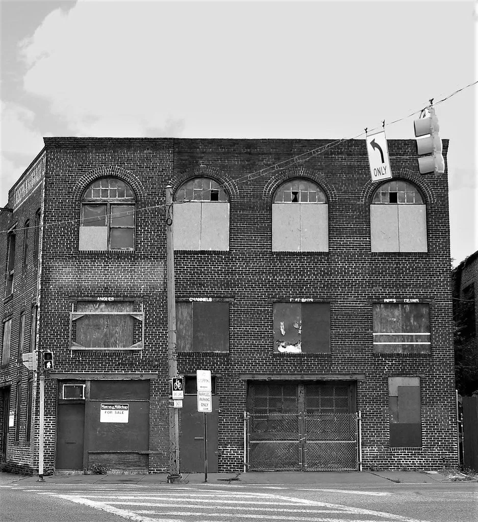 Brick warehouse façade with boarded windows.