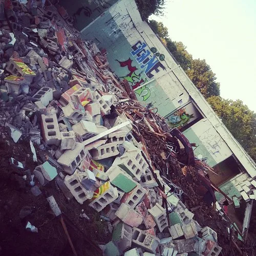 Ruine de bâtiment tagué devant un amas de parpaings et de débris.