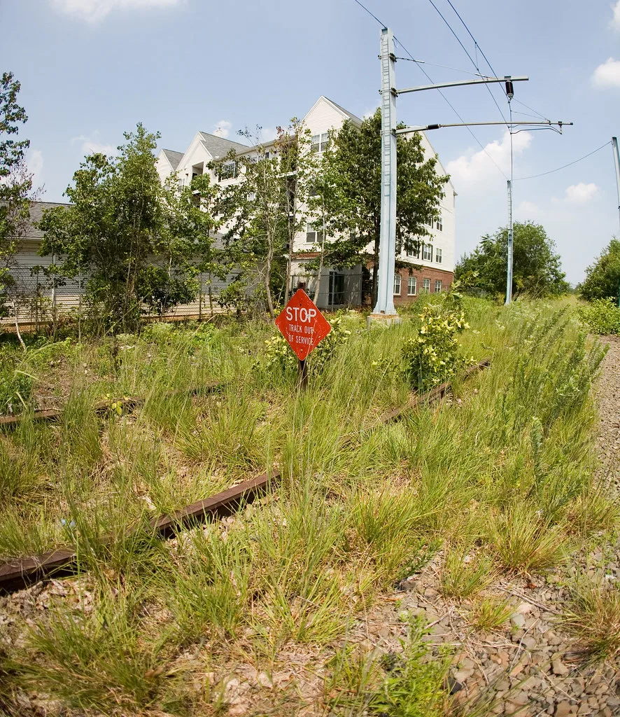 Old overgrown railway track with an out-of-service sign.