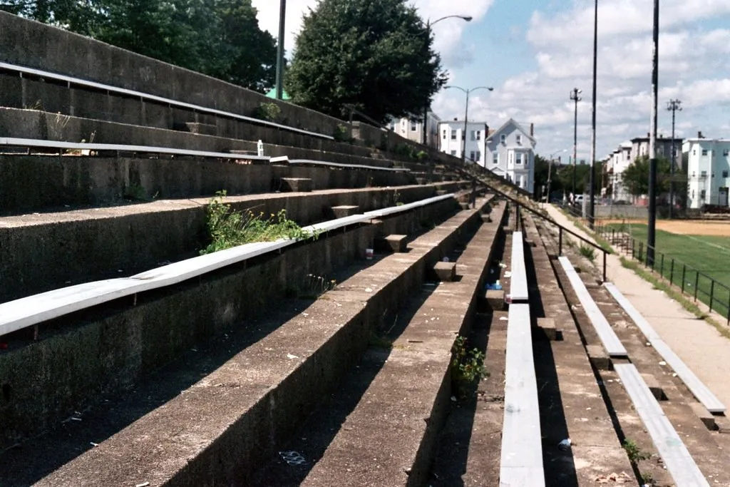 Old grandstand with damaged seats and vegetation growing on its steps.