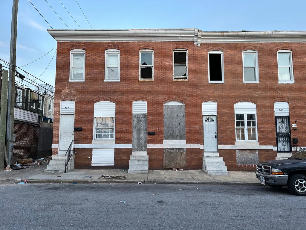 Maison mitoyenne de briques condamnée entre des façades voisines entretenues.