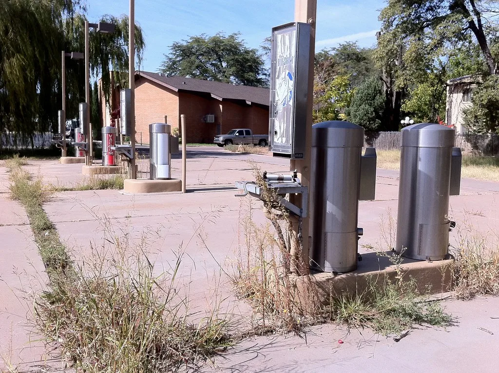 Old car wash equipment on a grass-covered concrete surface.
