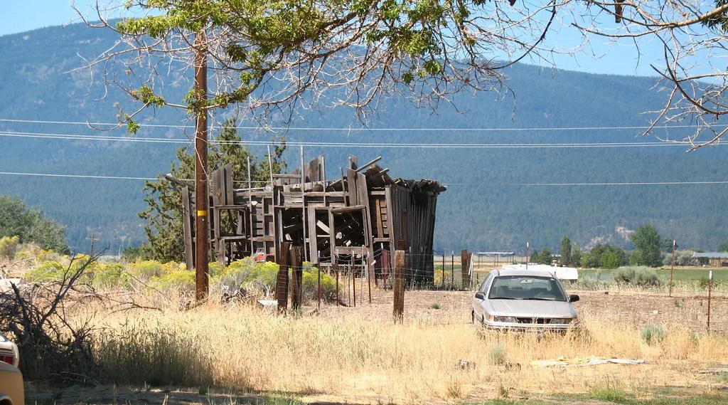 Ruined wooden building frame in front of mountains.