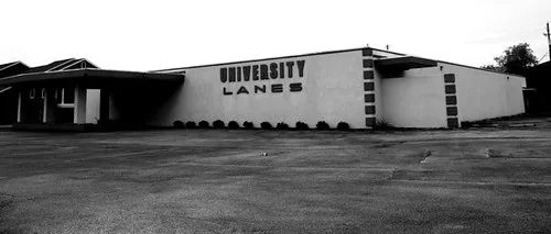 Old University Lanes bowling alley beyond an empty car park, in black and white.