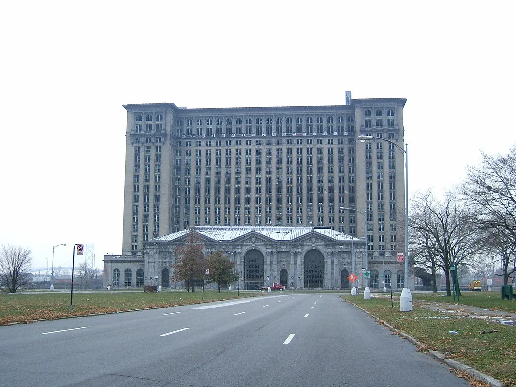 Large old station with many broken windows at the end of a road.