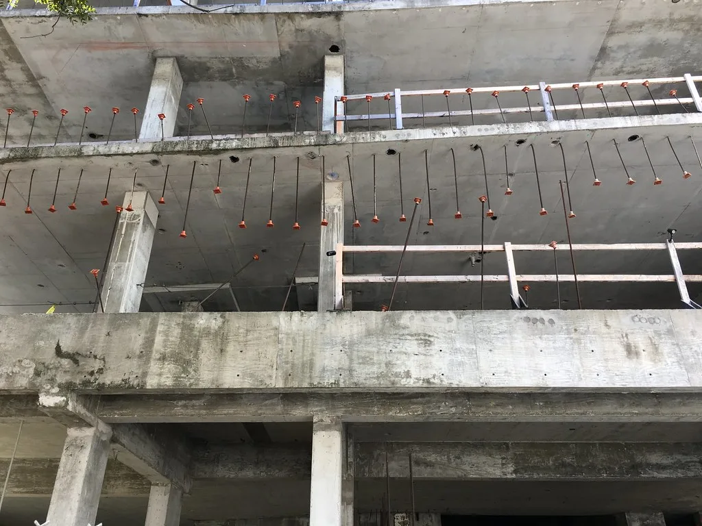 Étages ouverts d’une ossature de béton inachevée, avec armatures apparentes.