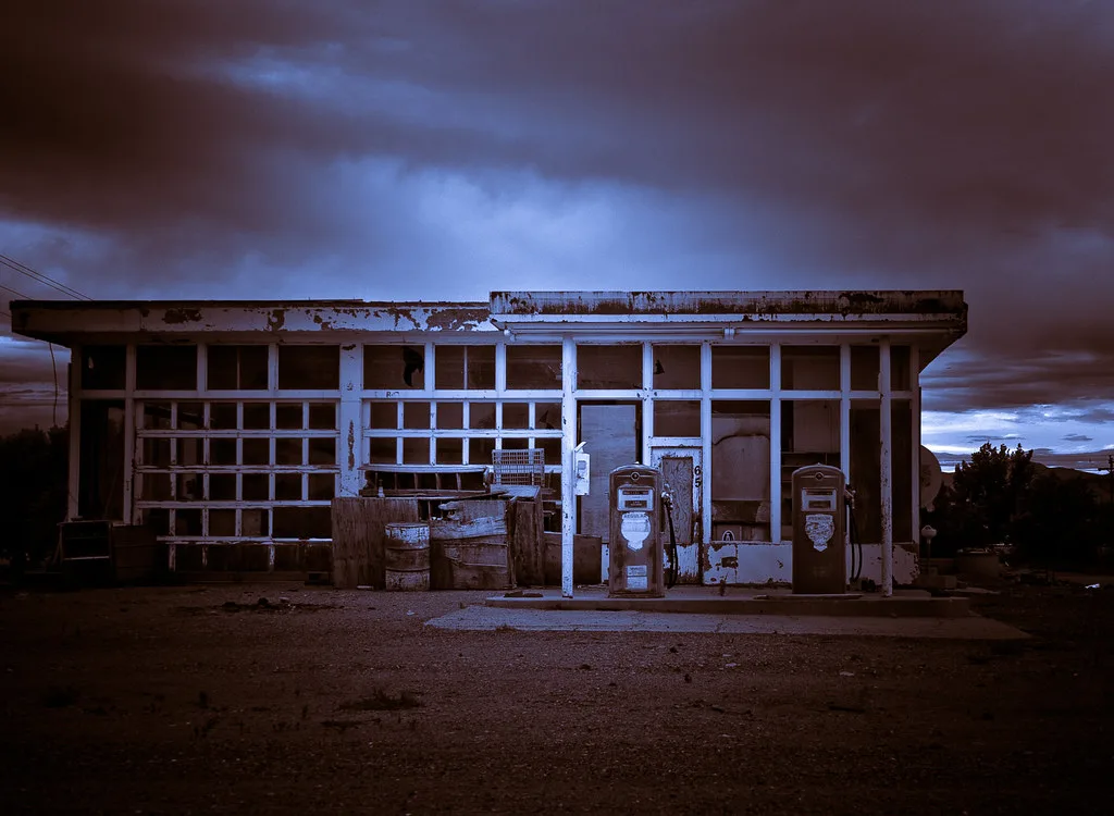 Decaying former petrol station with two fuel pumps.