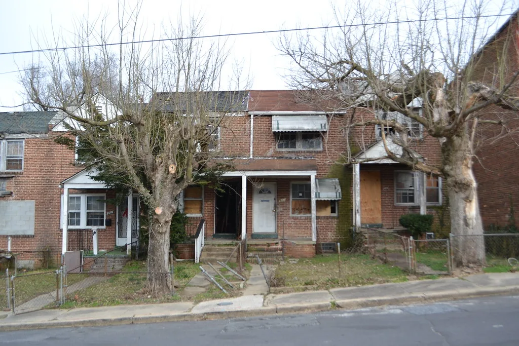 Brick row houses with boarded openings and sagging fences.