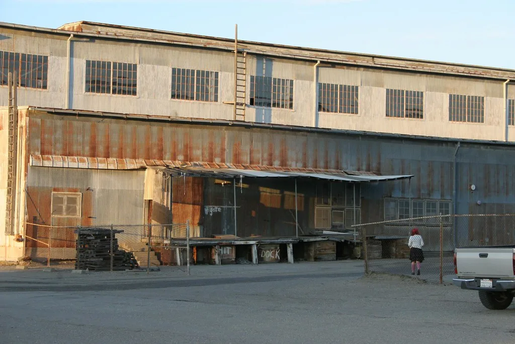 Old rusty metal warehouse with a deteriorated wooden loading dock.