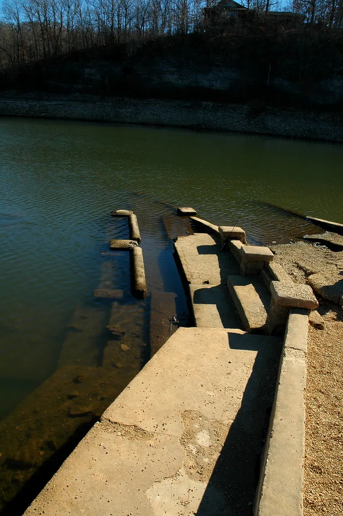 Anciens gradins de béton partiellement recouverts par l’eau.