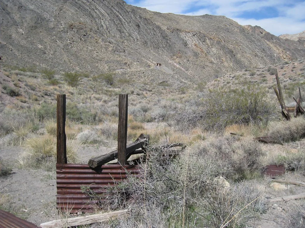 Vestiges de bois et de tôle rouillée dans un paysage rocheux.
