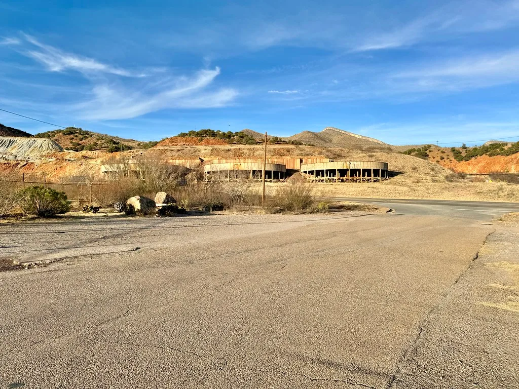 Old low building with curved facades and open bays below arid hills.