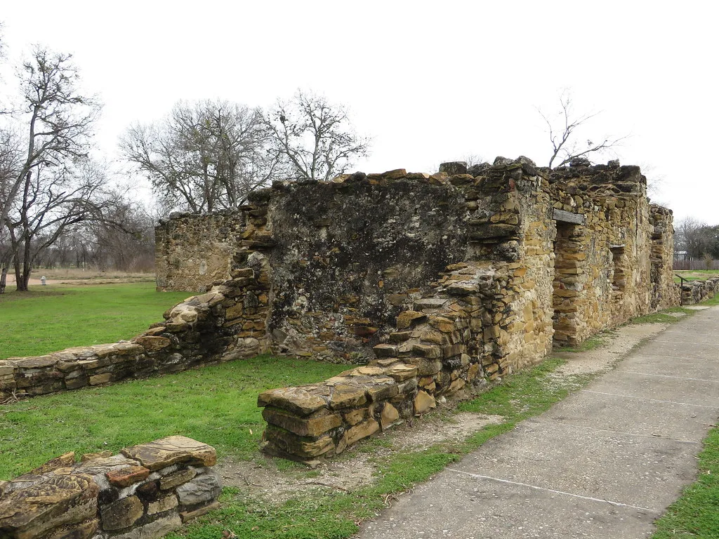 Stone building ruins with partially collapsed walls beside a path in a park.