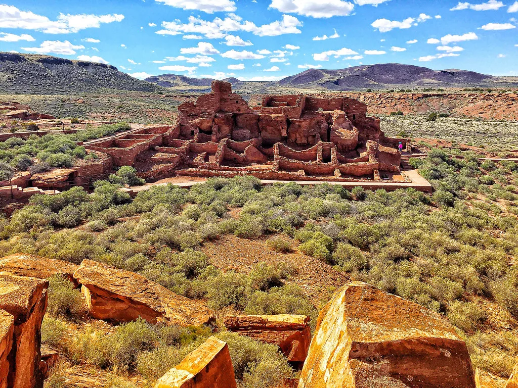 Ruins of red stone buildings in a desert landscape.