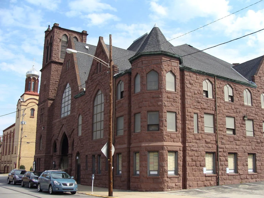 Red-stone Homestead United Presbyterian Church with a bell tower and turret.