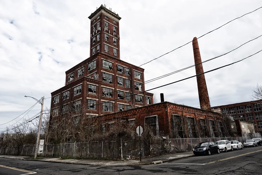 Brick factory with a tall tower and broken windows.