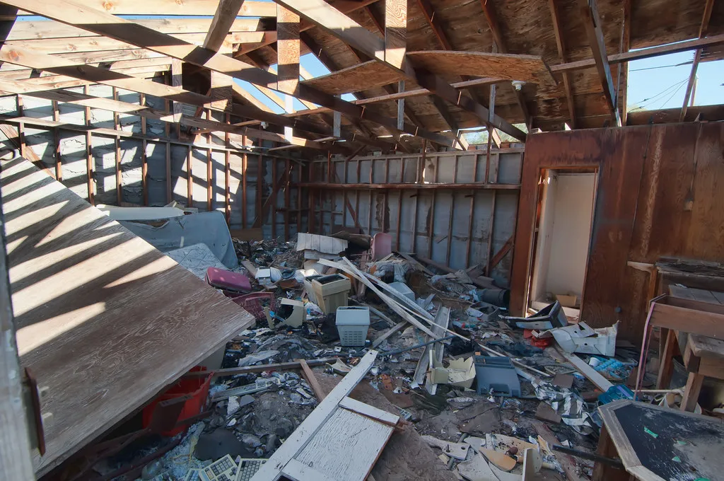 Old interior with a torn-open roof and a floor covered in rubble and equipment.