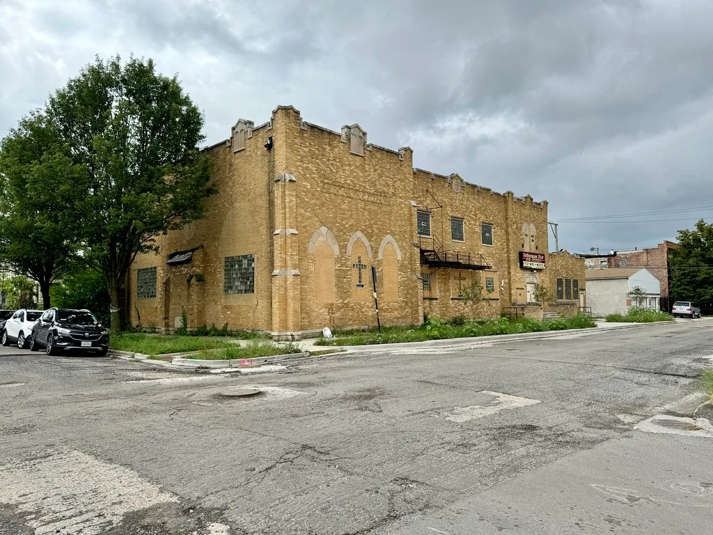 Old yellow brick religious building with sealed entrances.