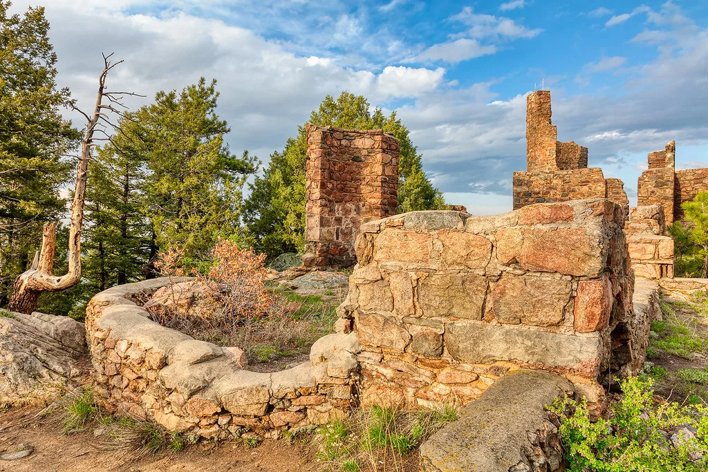 Stone ruins with walls and chimneys among trees.