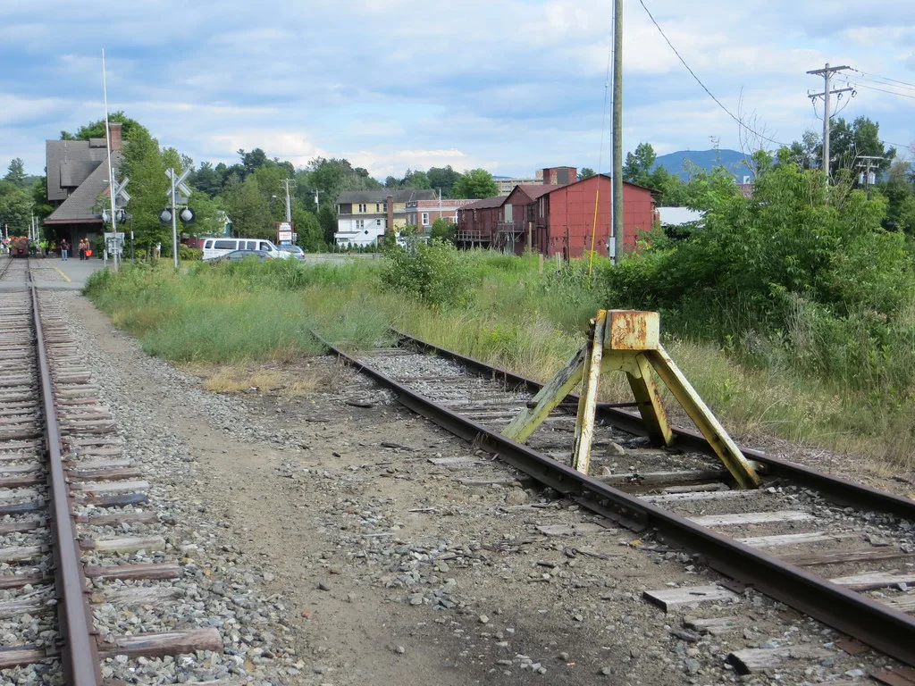 Old dead-end railway siding with a rusty buffer stop and tall grass.