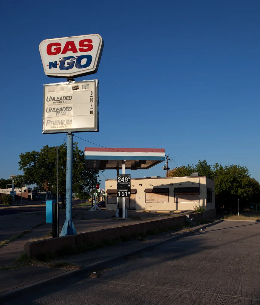 Former fuel station with boarded windows beneath a tricolour canopy and a Gas N Go sign.