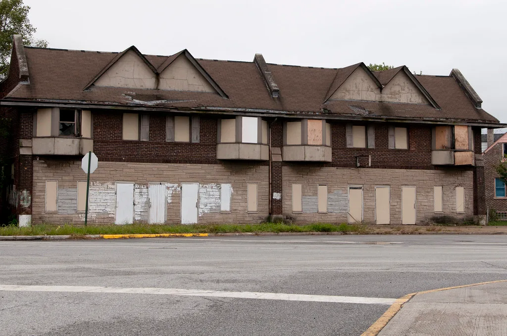 Old brick building complex with boarded doors and windows.