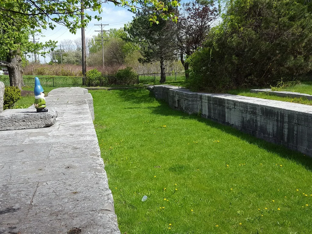 Murs de pierre d’un ancien canal asséché rempli d’herbe.