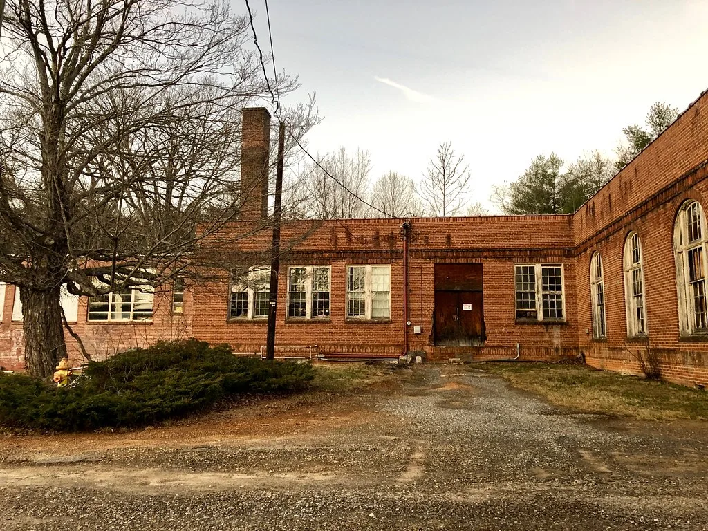 Old brick building with deteriorated windows around an empty courtyard.
