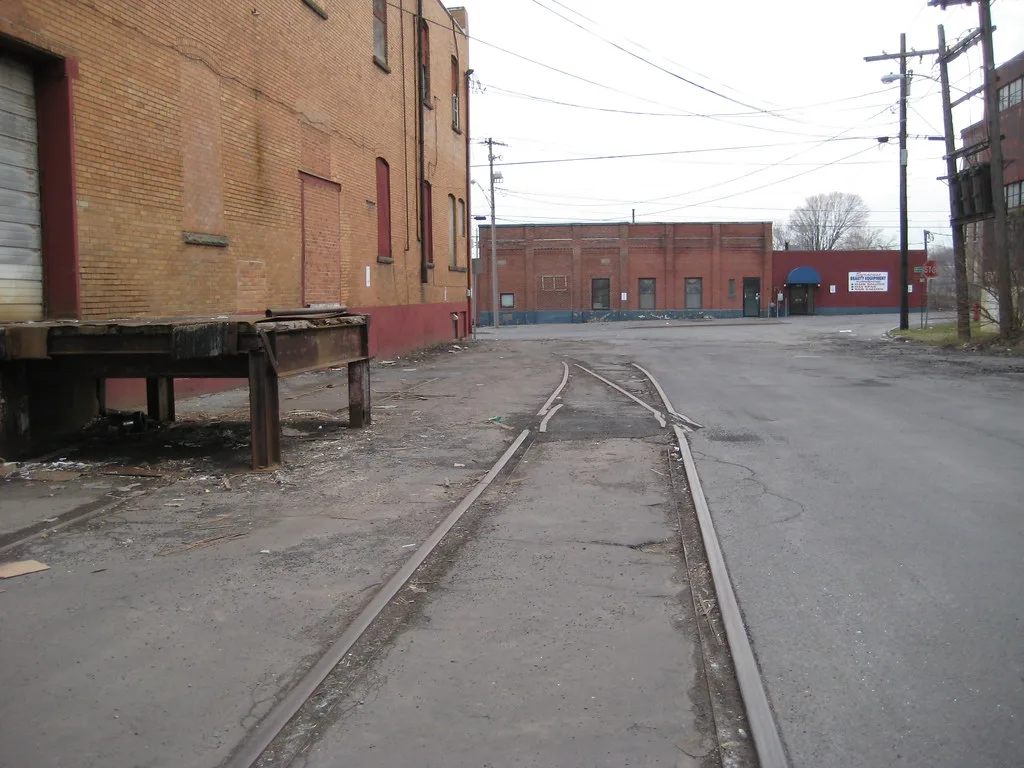 Rails of an old siding alongside an industrial building.