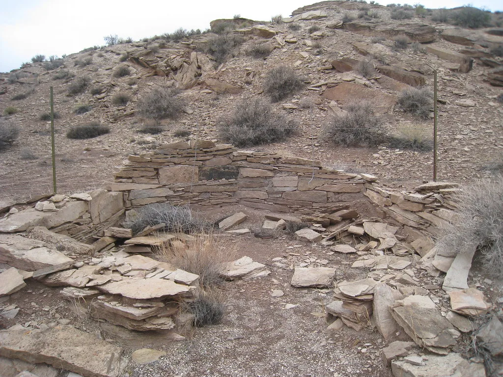 Vestiges de murs bas en pierre dans un paysage désertique.