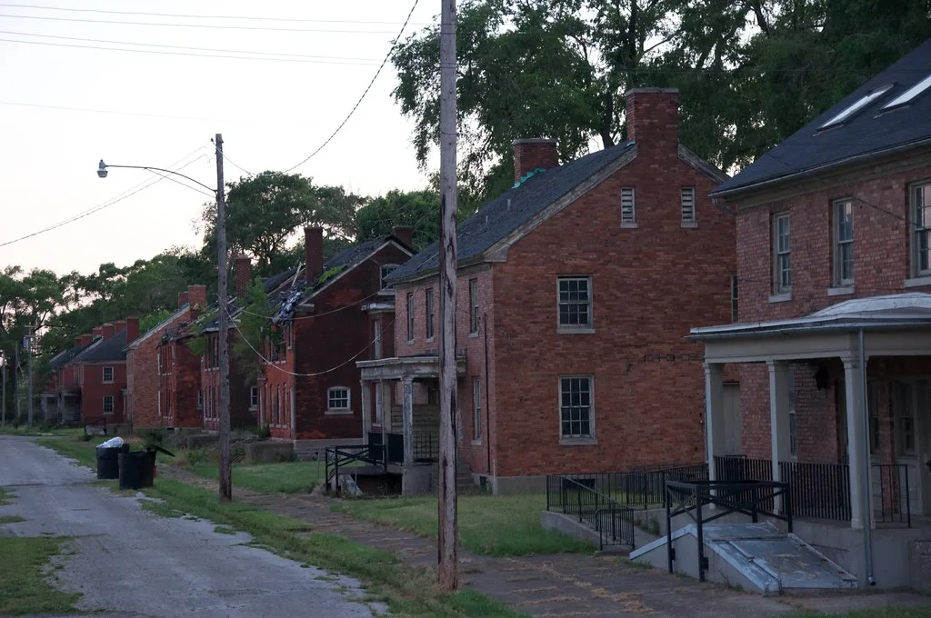 Row of old brick buildings with several damaged roofs.