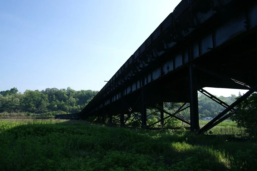 Ancien ouvrage métallique sur de hauts supports dans une prairie.