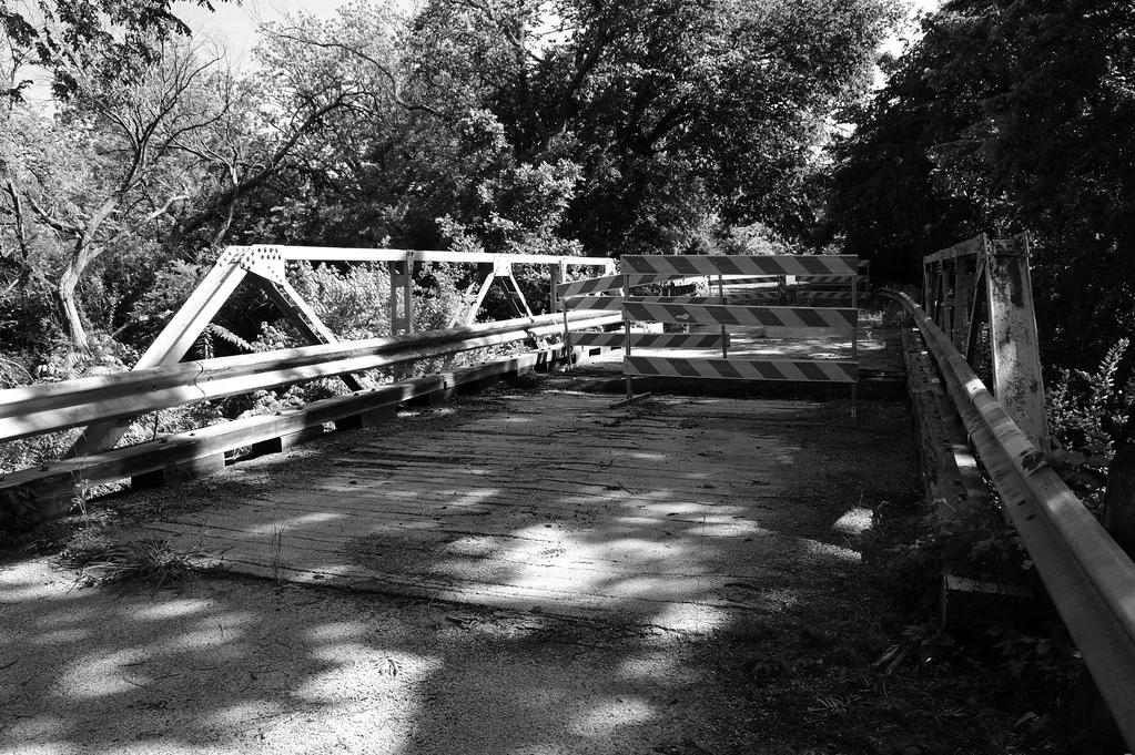 Old metal bridge closed with barriers, in black and white.